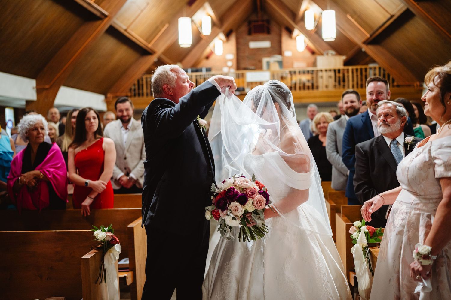 Wedding celebration inside a rustic wooden barn venue with warm lighting illuminating the joyful gathering.