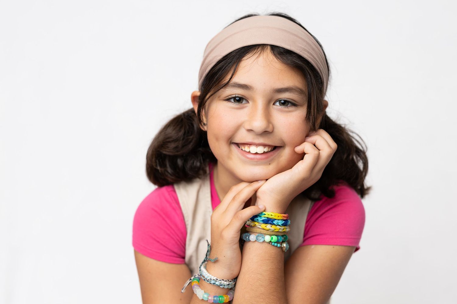 Studio portrait with pink shirt and baseball cap against white background.