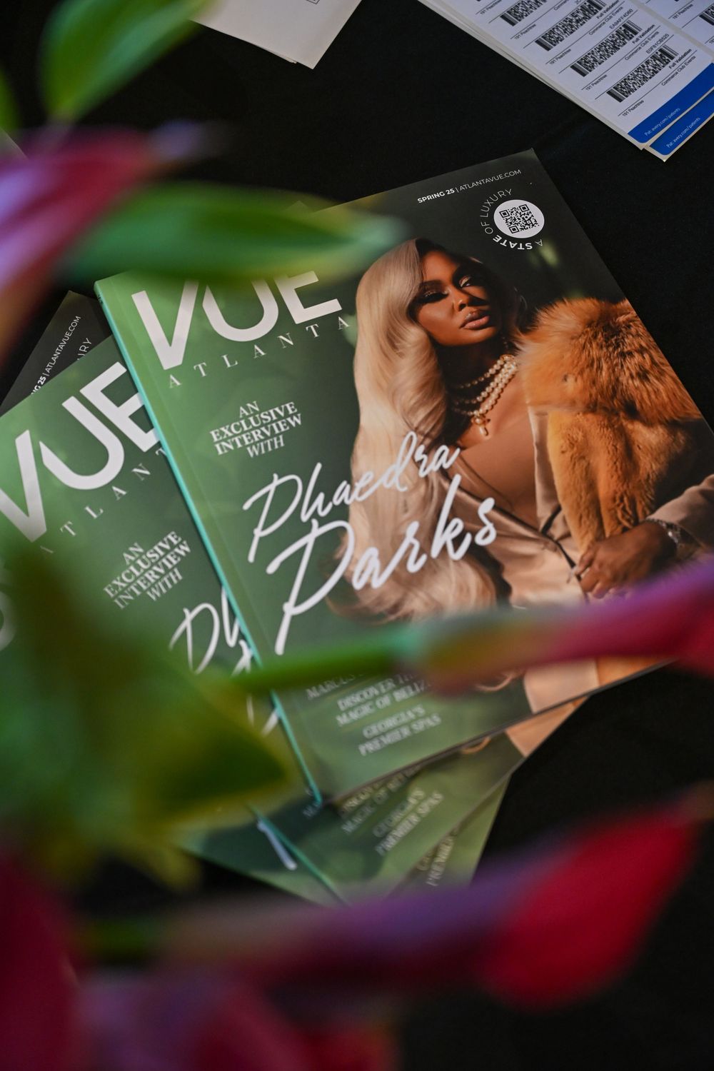 Green Vogue magazine covers displayed in a creative arrangement with blurred floral elements in the foreground.