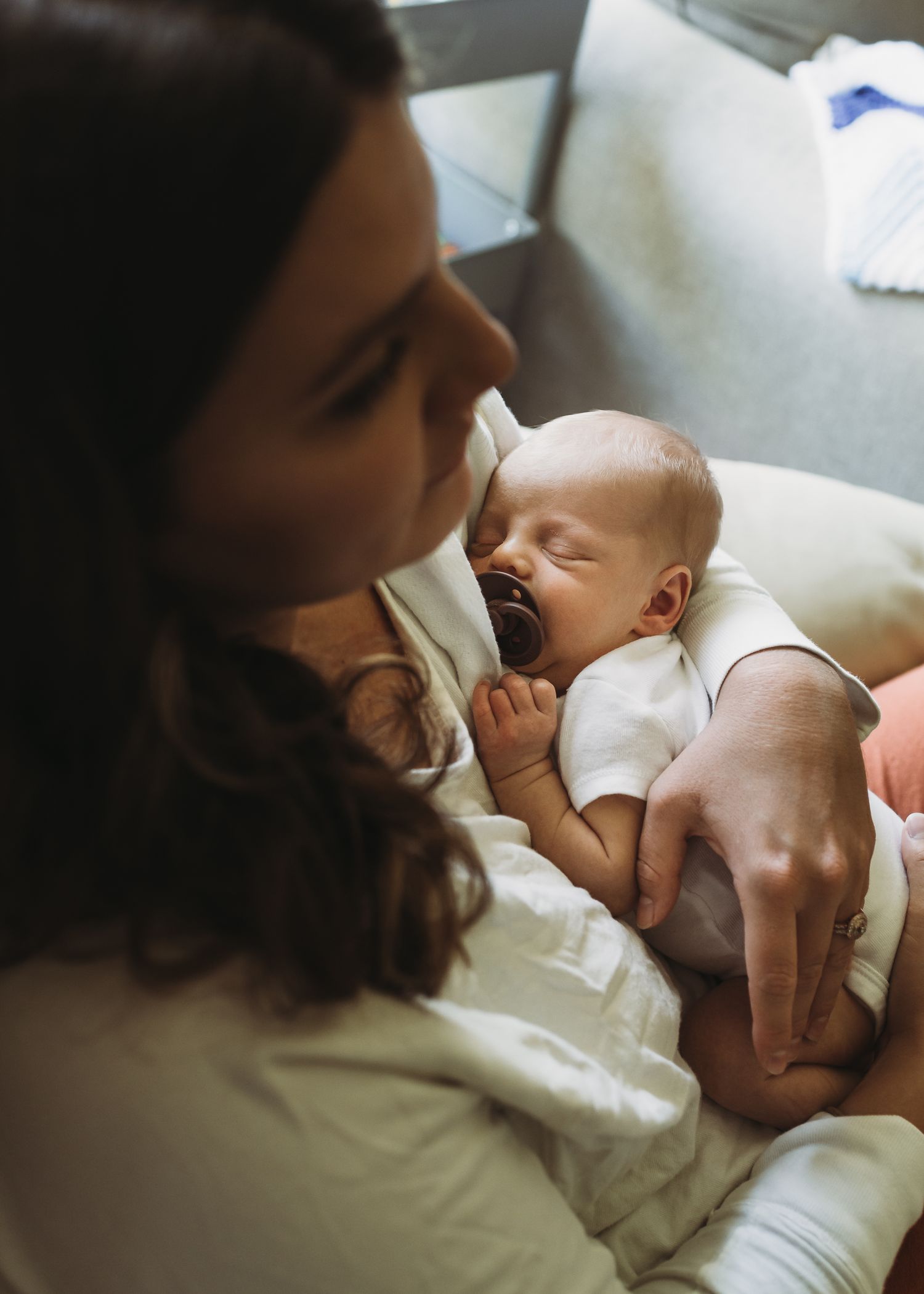 An intimate moment as a woman cuddles and nourishes a sleeping baby in a serene home setting.
