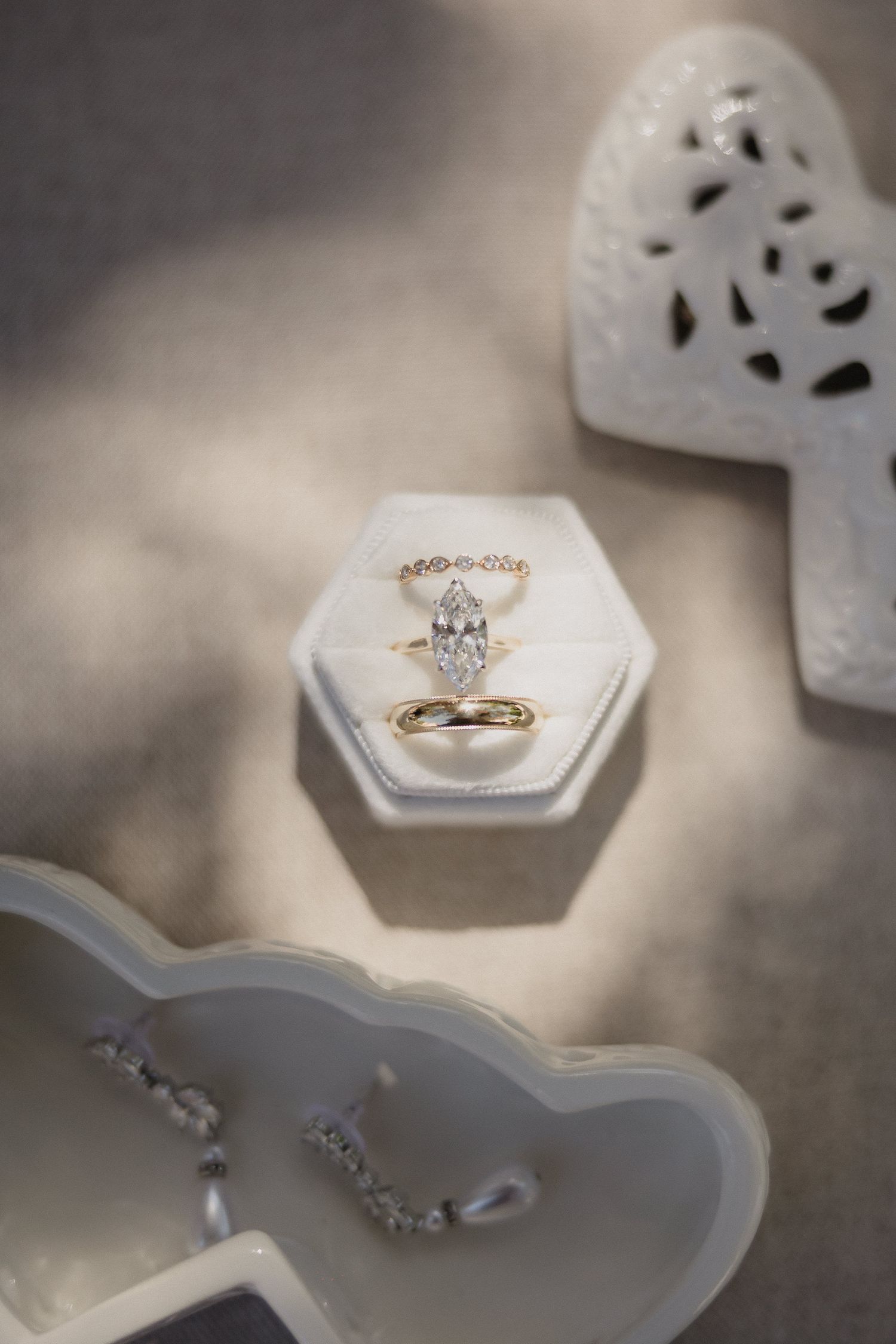 Wedding rings displayed in white hexagonal box with decorative elements.