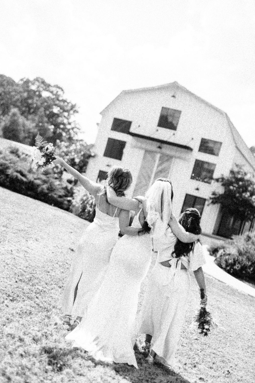 Black and white photo series showing wedding party motion sequence walking across an open field near a white building.