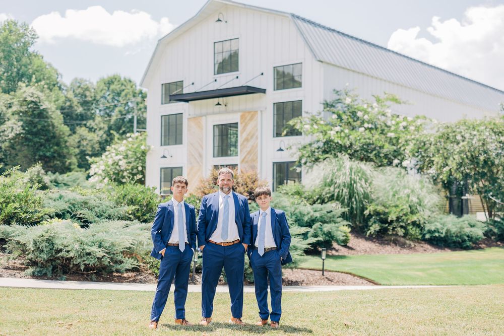 A series of six photos showing a white barn-style building with groups of people in navy blue suits posing outside.
