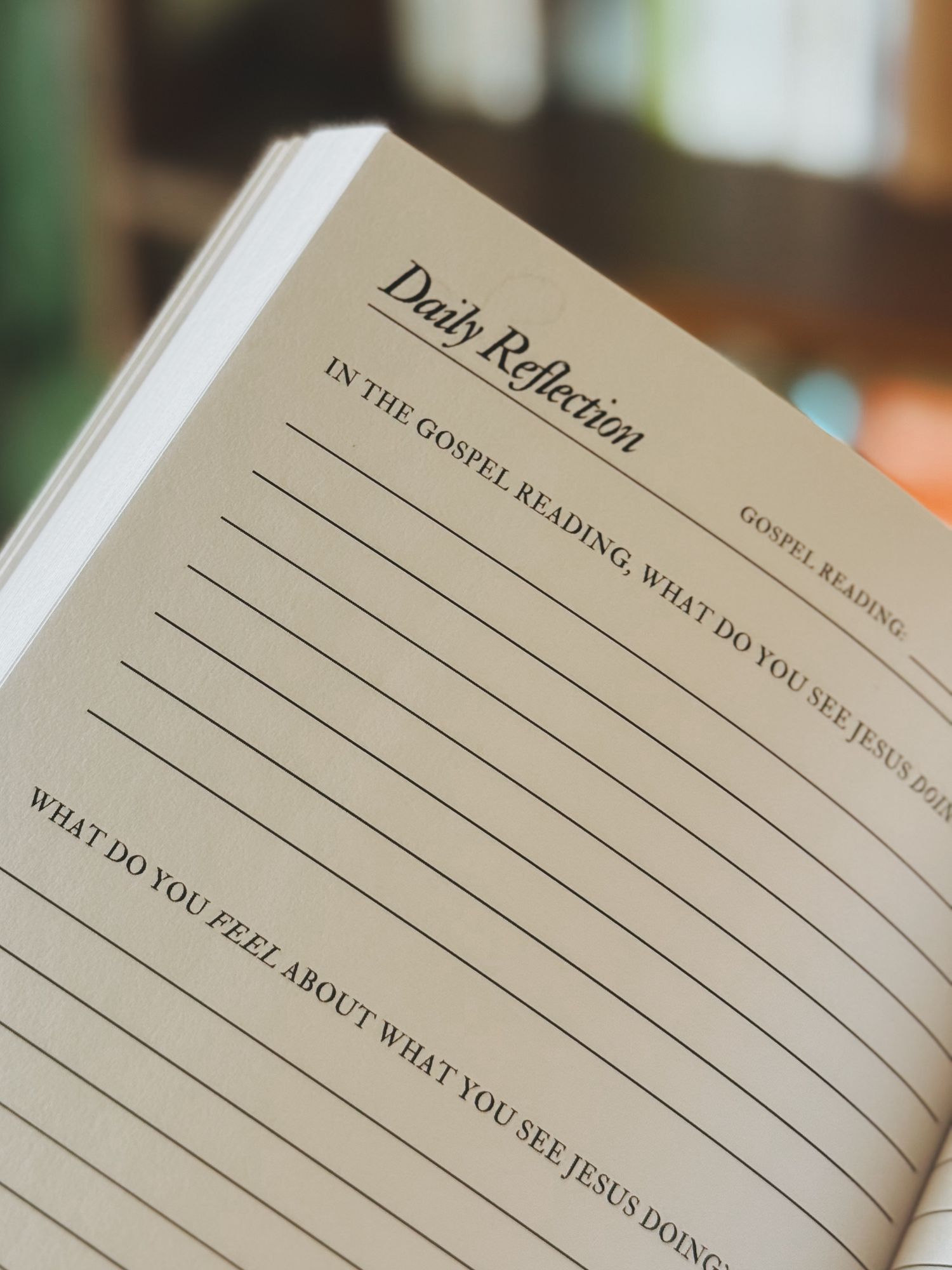 A close-up view of an open journal or diary with blank lined pages showing prompts for daily reflections.