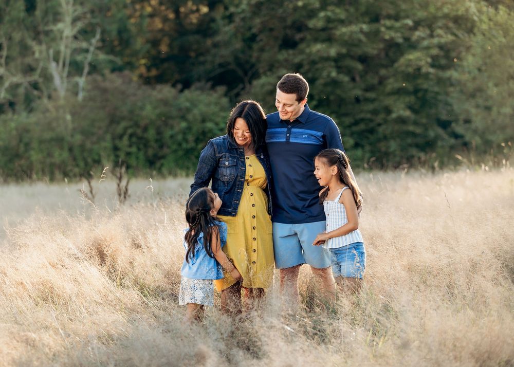 A family enjoying a tender moment together in a golden wheat field at sunset.