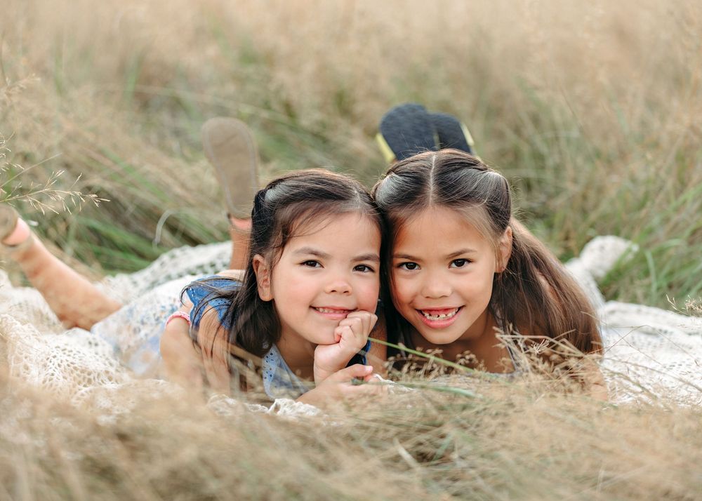 Two children lying in golden grass during an outdoor photo session.