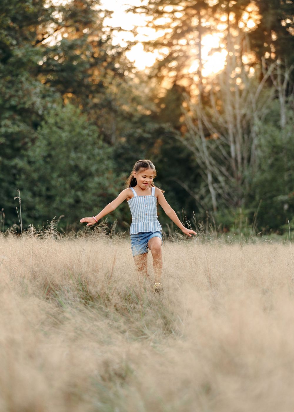 A child running joyfully through tall grass at sunset.