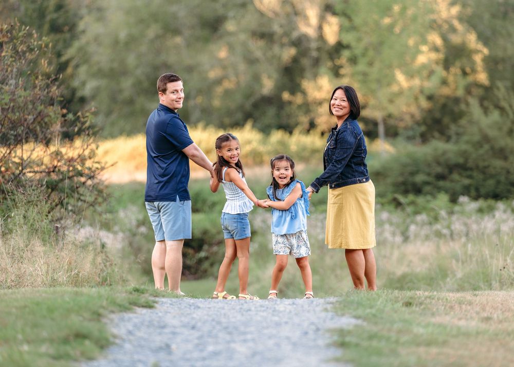 A family of four posing together on a dirt path during golden hour.