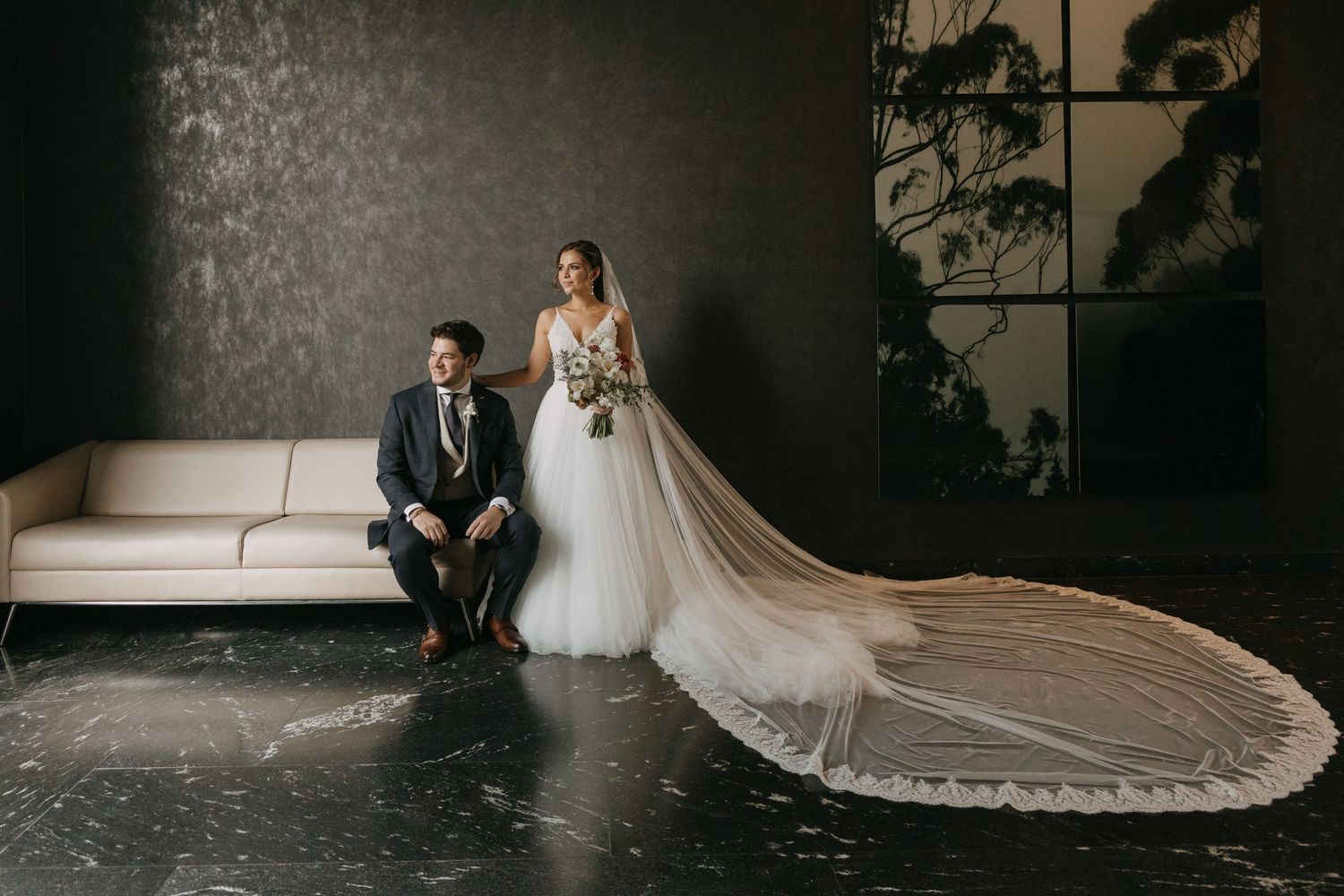 Artistic black and white wedding portraits showing a bride's flowing dress train against a textured wall.