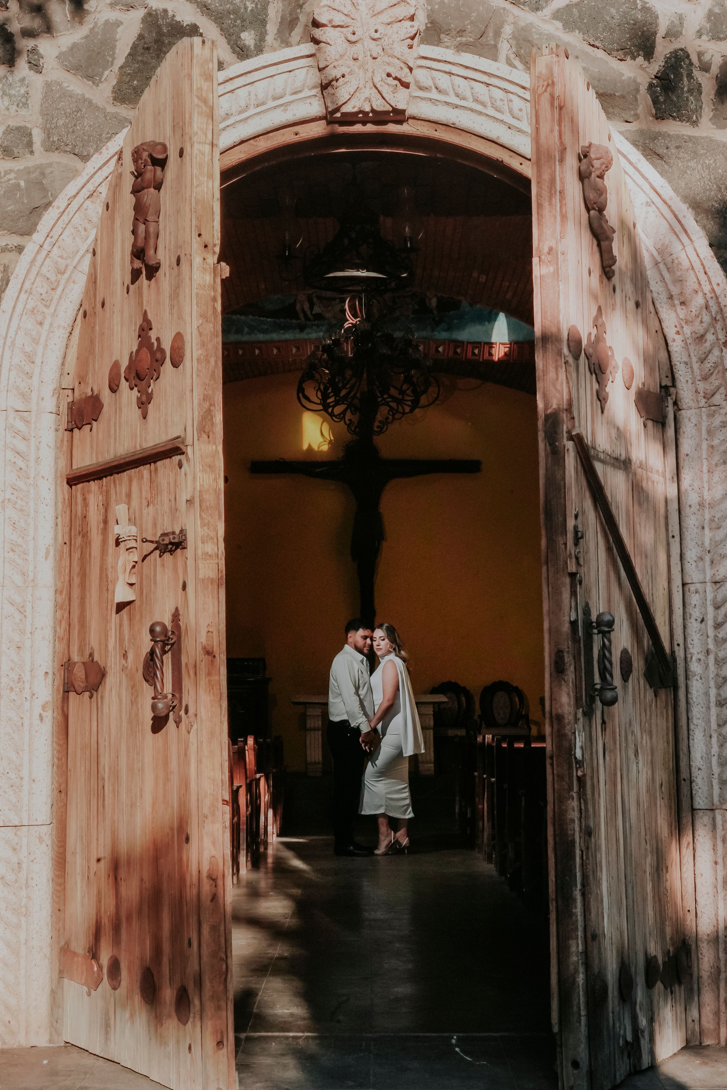Architectural details of stone arches and rustic wooden doors create a romantic corridor in a historic building interior.
