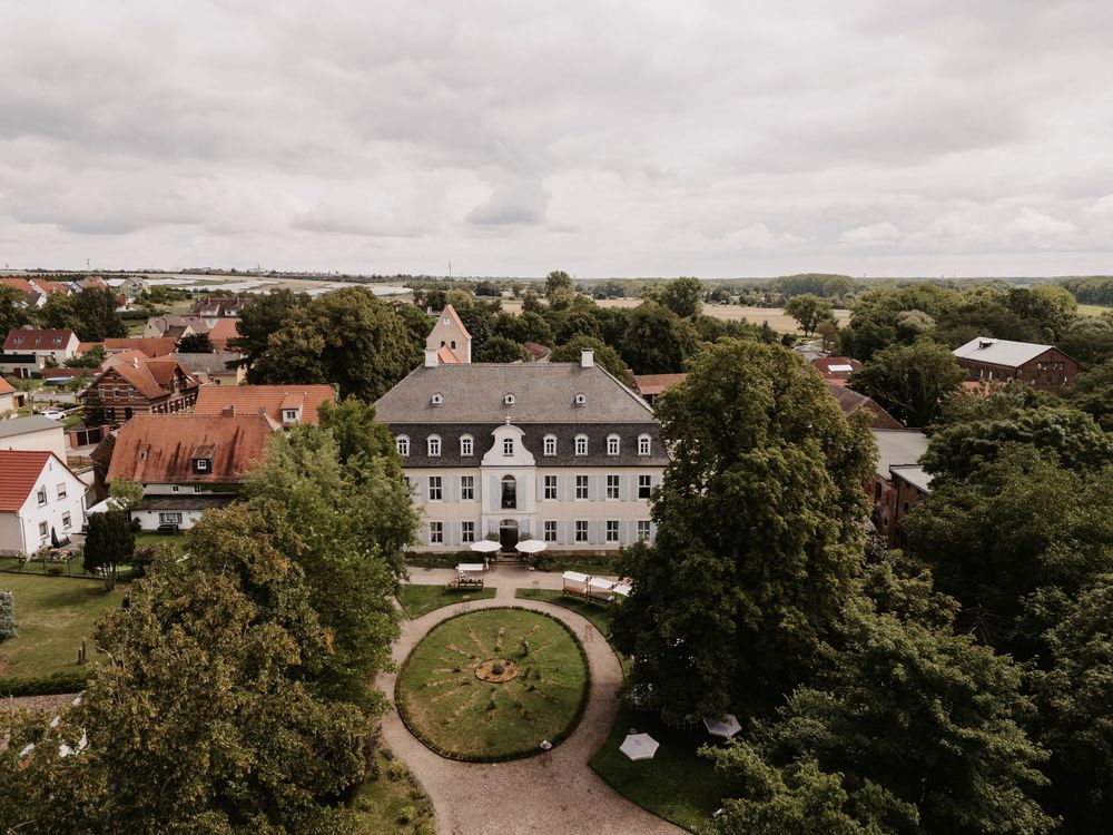 Aerial drone footage shows luxury estates and mansions nestled among lush green trees in an upscale residential neighborhood.