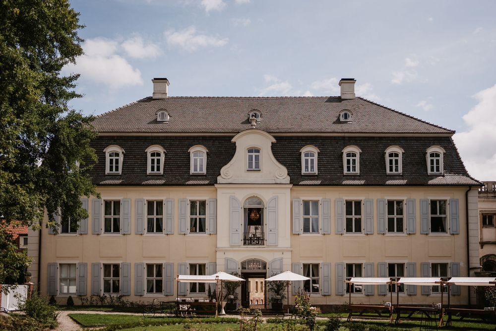 A stately manor house with dormer windows and symmetrical architecture photographed under blue skies.