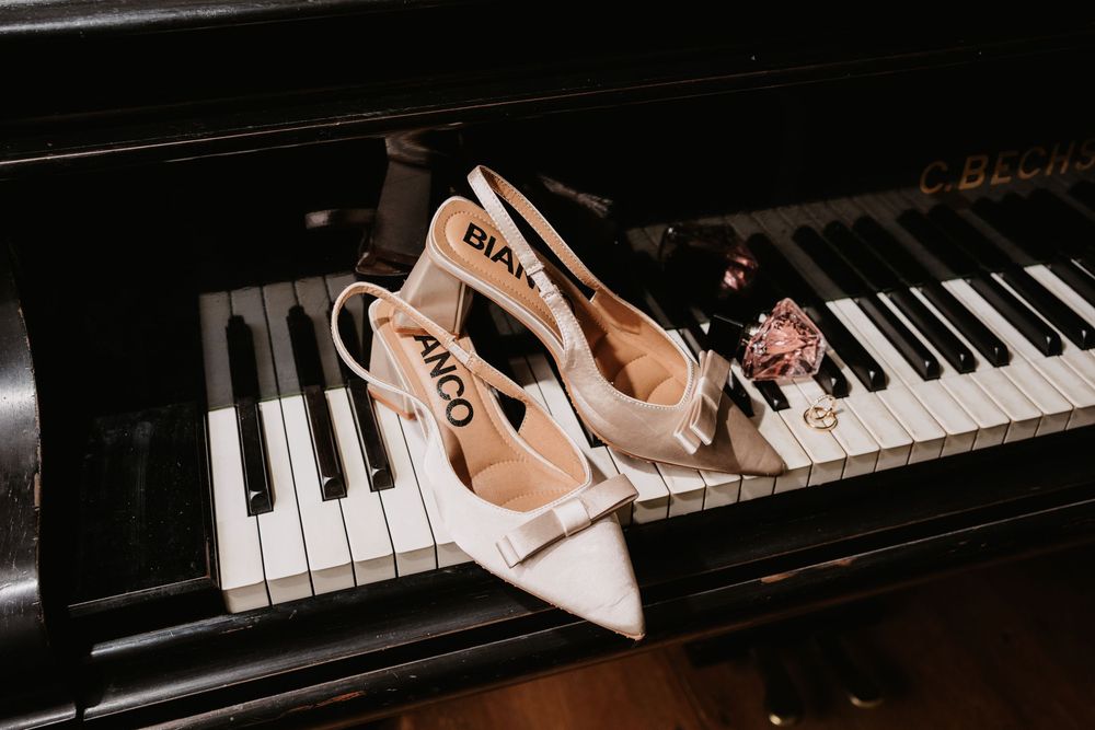 Two ballet pointe shoes rest elegantly on piano keys in dramatic lighting.