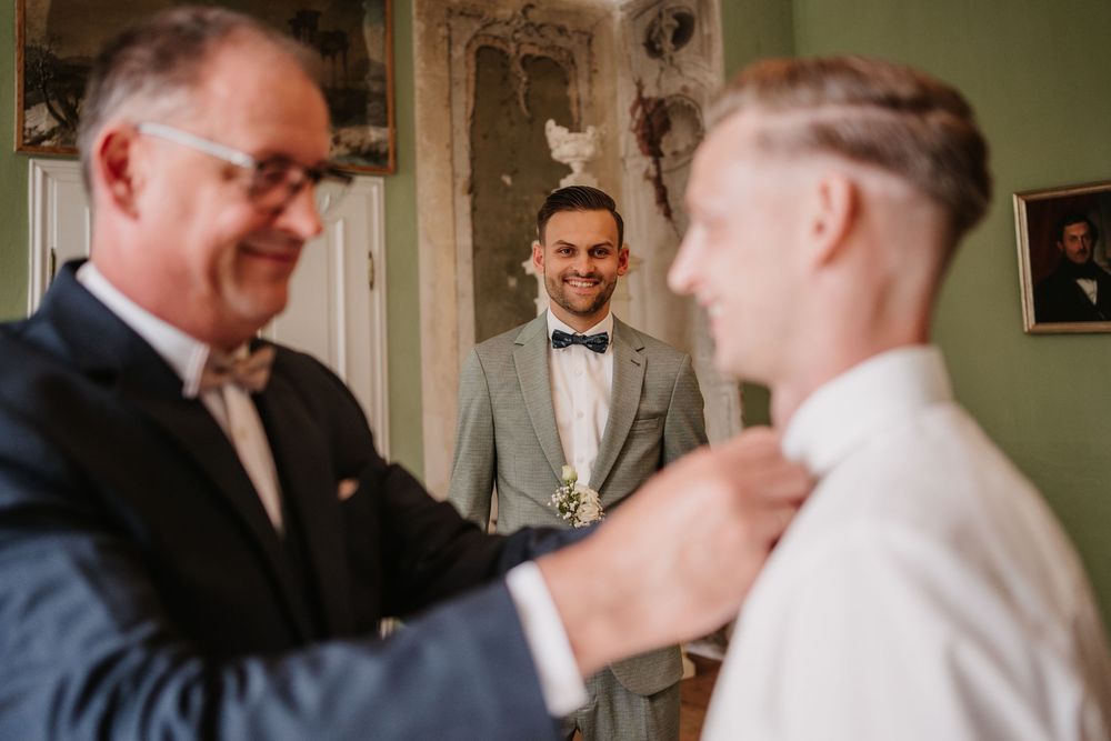 A groom with his companions in formal attire share joyful moments during a wedding celebration.