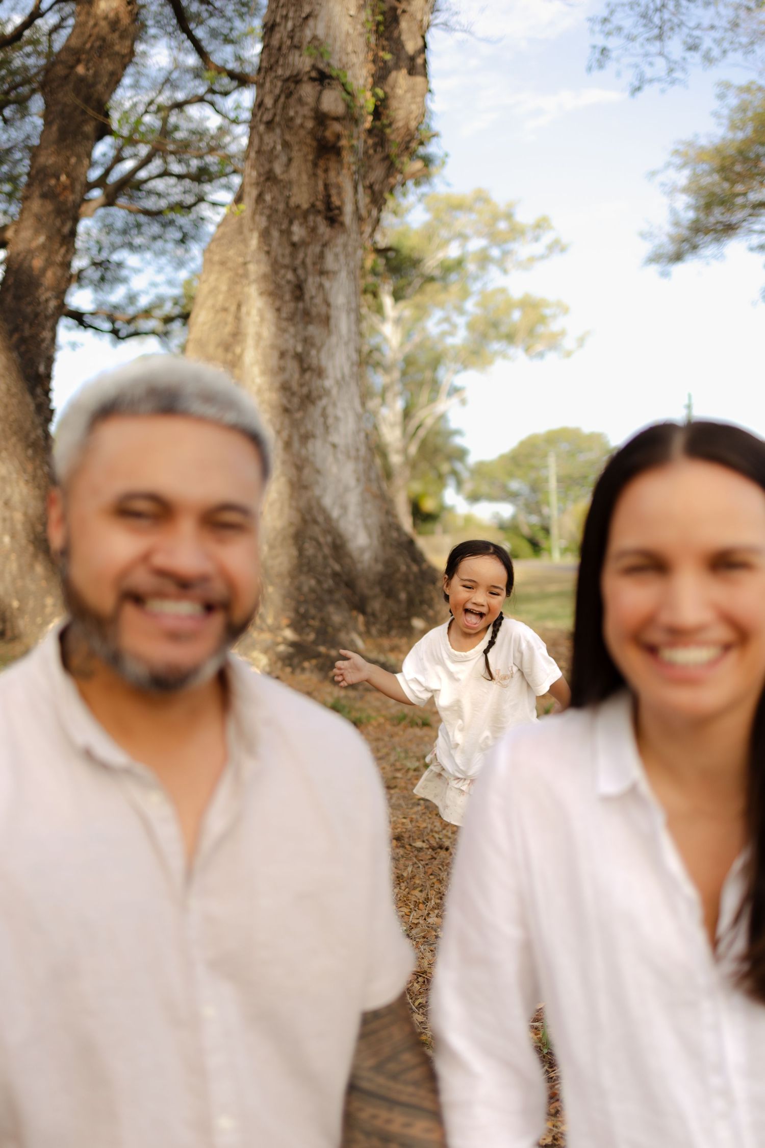 A playful outdoor photoshoot sequence showing joyful expressions and laughter under tall trees.