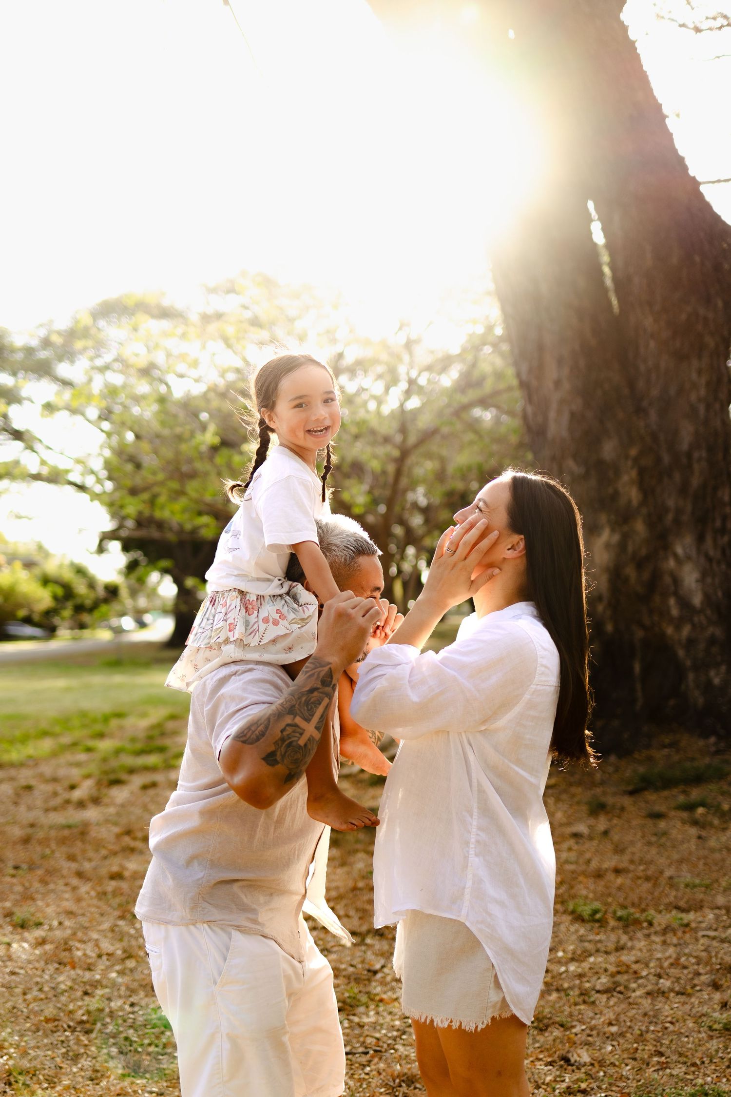 Candid family moments captured in golden sunlight beneath a large tree.