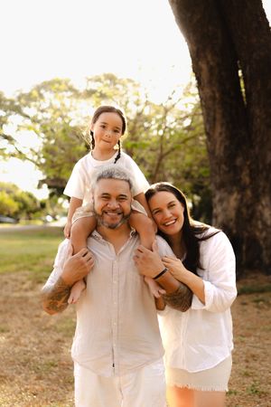Happy family embracing and smiling during an outdoor photo session in white attire.