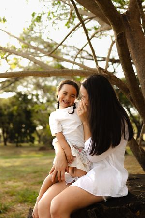 Tender family moments captured during an outdoor photoshoot under trees.