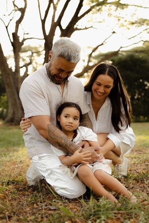 A loving family portrait outdoors with everyone dressed in white clothing.