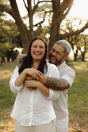 A couple sharing a candid laughing moment together in a park setting.