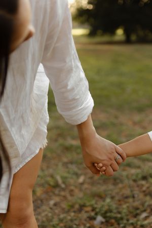 Close-up of hands holding together while walking outdoors.