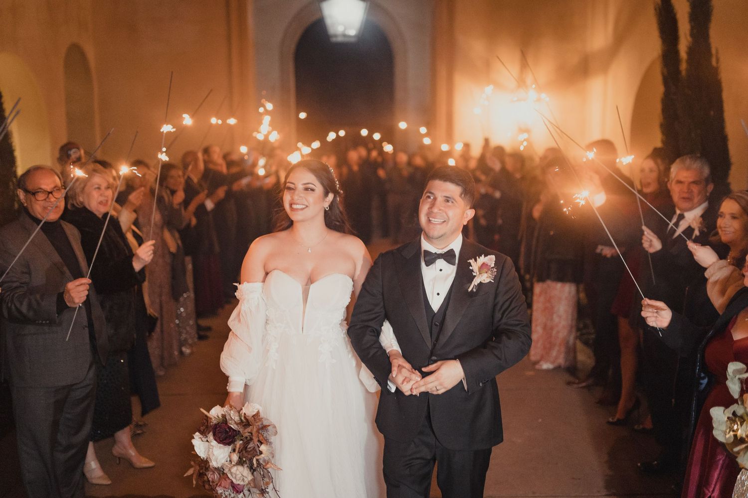 A couple exits reception with guests holding sparklers during an elegant wedding ceremony for Sacramento wedding