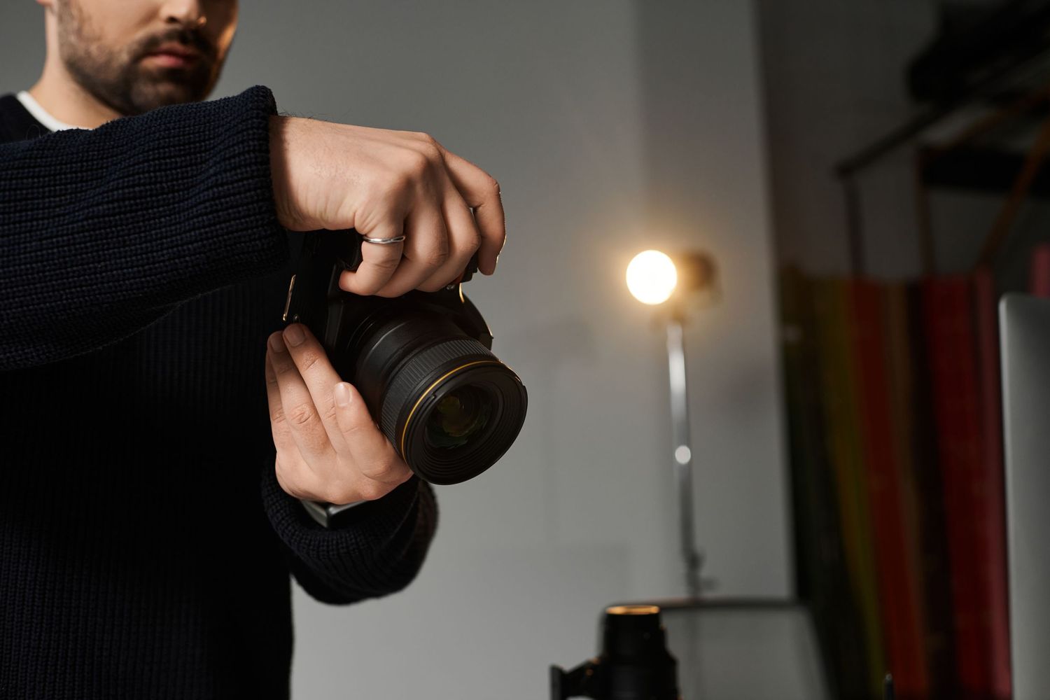 A person holds up a black camera lens against a light source to inspect it for dust and damage.