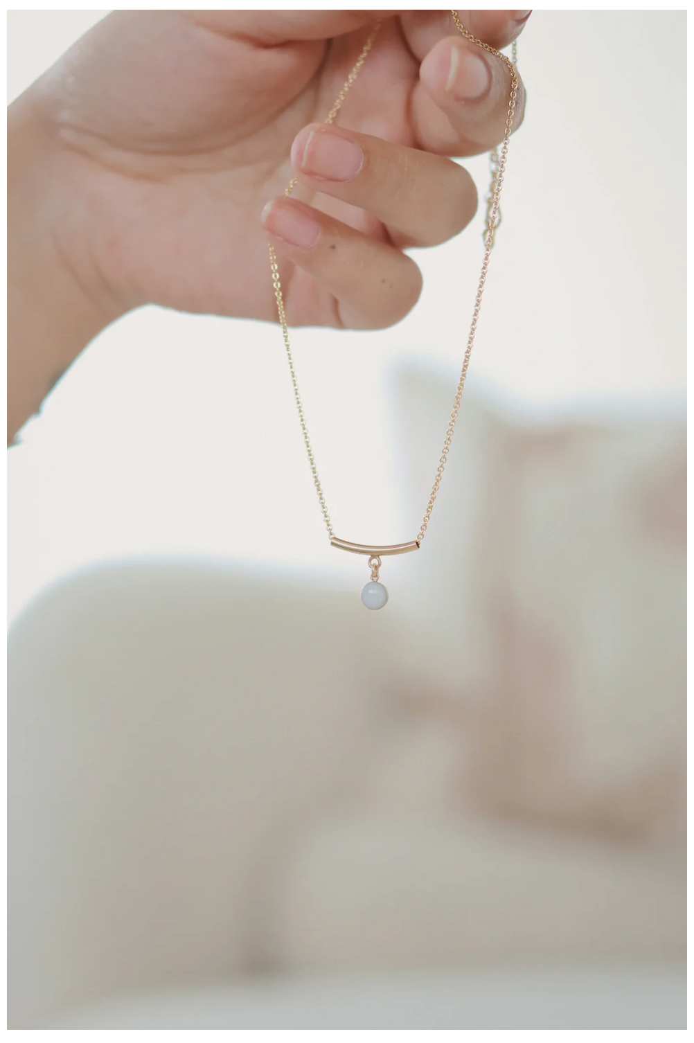 Close-up series showing delicate gold necklaces with minimalist bar and circle pendant designs against soft white background.