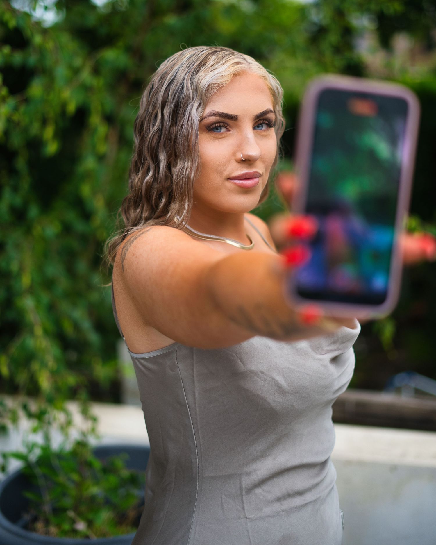 Person in gray sleeveless top poses in front of green foliage backdrop in dynamic progressive shot sequence.