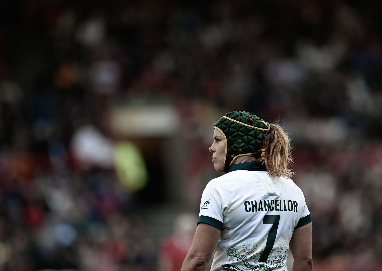 Rugby player in dark jersey prepares to catch a ball during a competitive match.