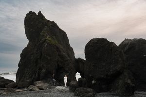 Dramatic aerial view of rugged coastal cliffs with waves crashing against dark rocks during overcast weather.