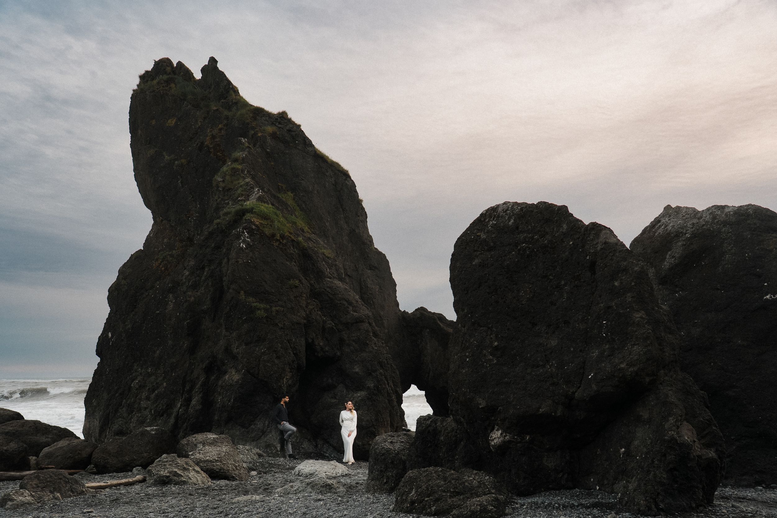 Dramatic aerial view of rugged coastal cliffs with waves crashing against dark rocks during overcast weather.