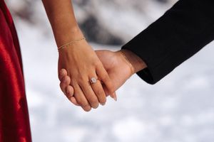 Two hands clasped together in a romantic gesture against a white background.