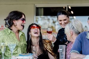 A group of friends enjoying wine and conversation outdoors at a casual gathering.