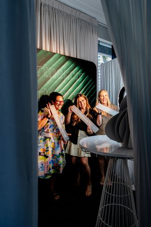 People dance and celebrate at a dimly lit party venue with dramatic curtain backdrop and lighting effects.