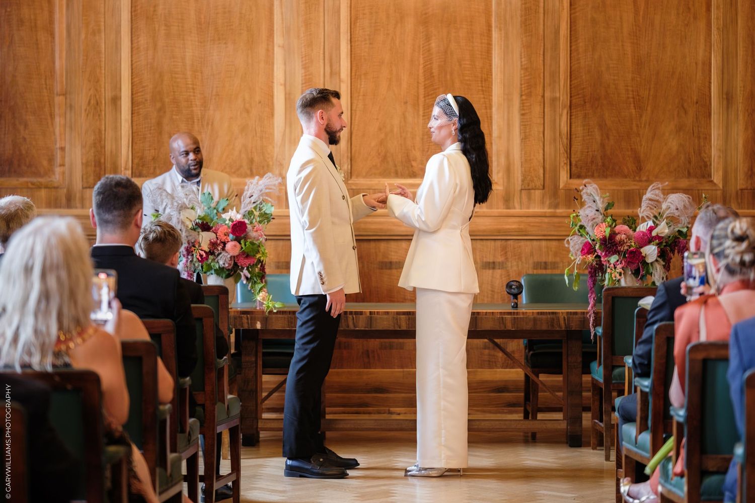 People gathered inside an elegant wood-paneled church or meeting hall during a formal ceremony or event.