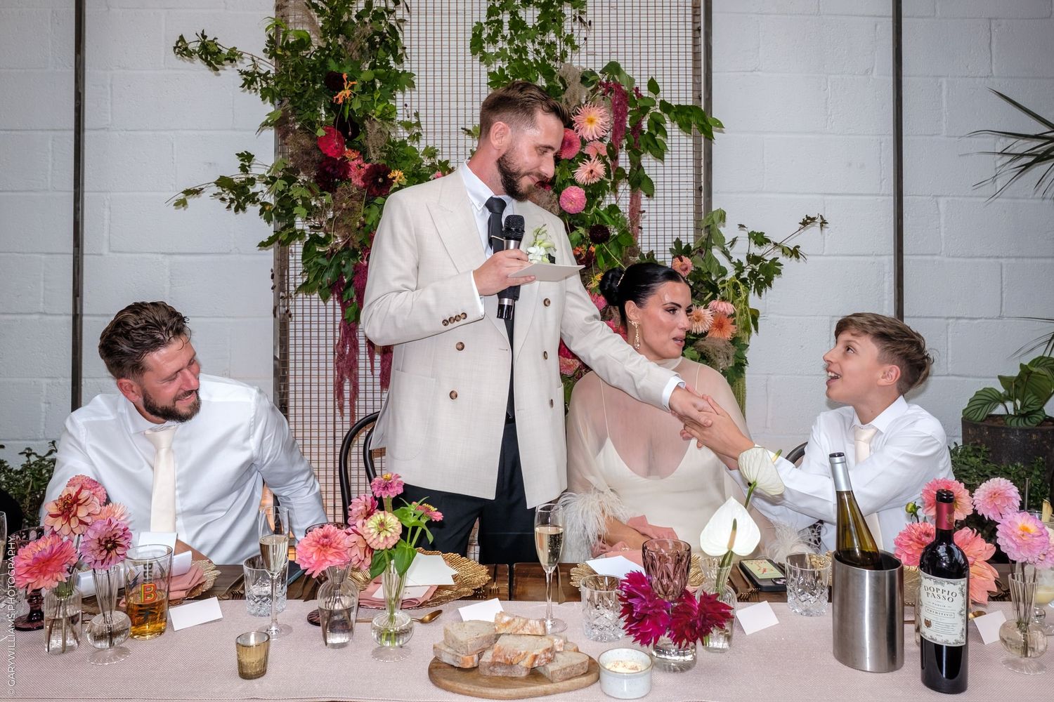 Group of guests seated at long tables decorated with pink floral arrangements enjoying a festive dinner party.
