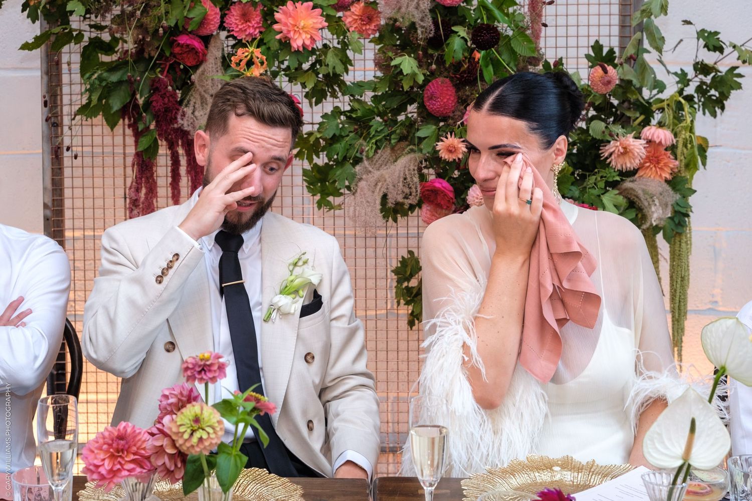 Festive wedding party poses emotively at a floral-decorated reception with pink and white decor.