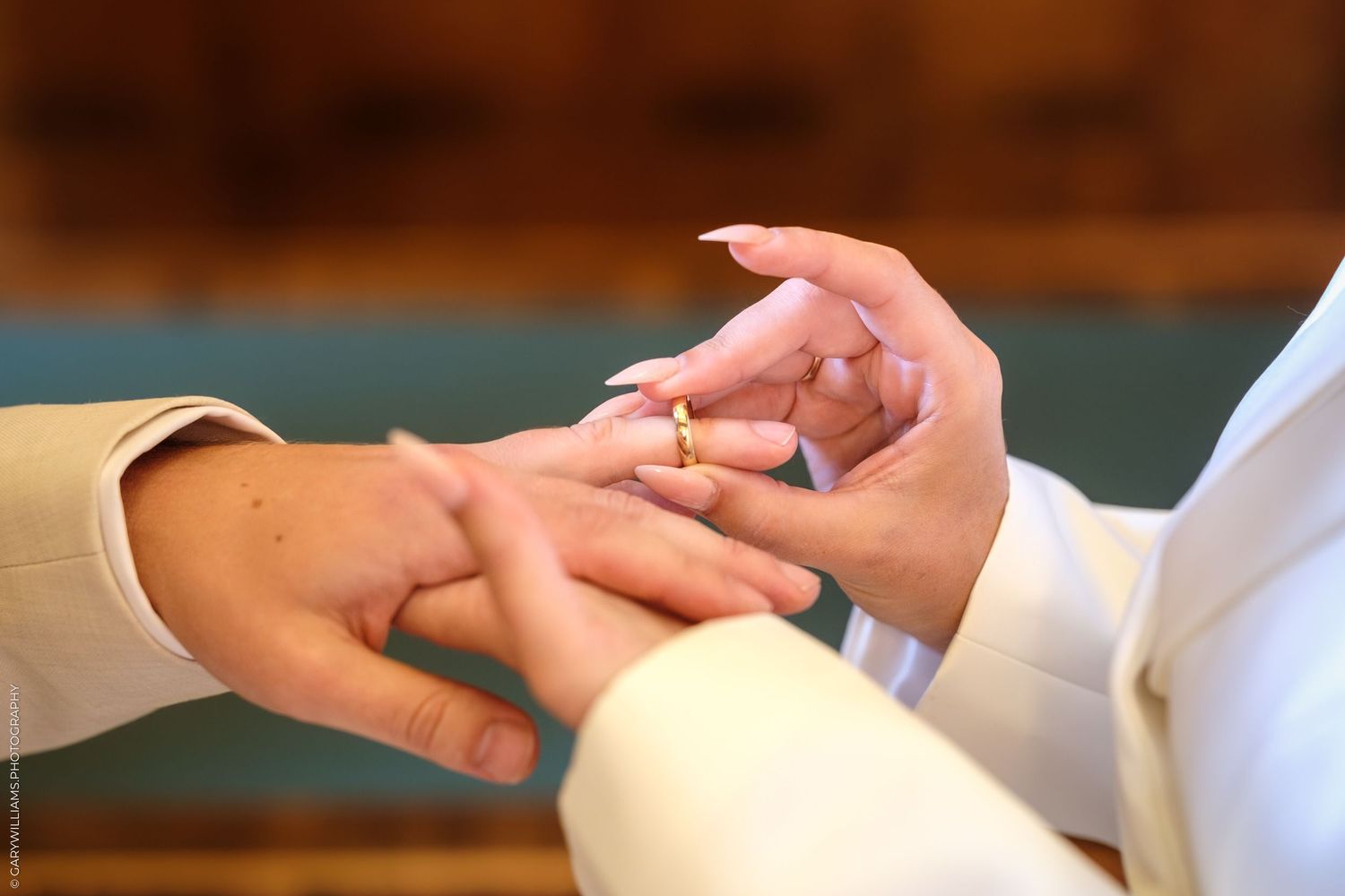 Close up shot of hands exchanging wedding rings during a marriage ceremony.