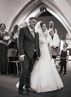 Candid black and white wedding photos show joyful dancing moments during a reception under arched architecture.