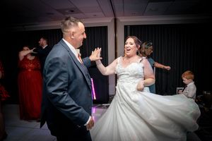A wedding couple dances and laughs together during their reception celebration on the dance floor.