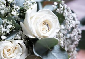White roses and delicate baby's breath flowers create an elegant wedding bouquet arrangement against a soft blurred background.