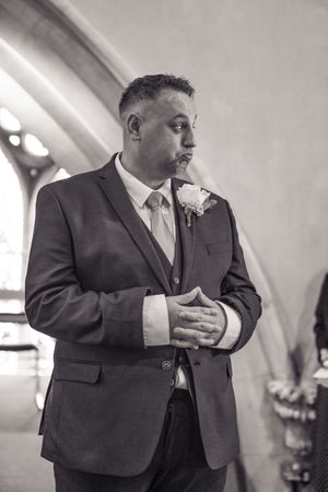 Groomsmen in dark suits and ties sharing a candid moment while laughing during wedding festivities.