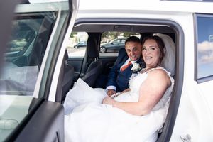 Bride and groom in white vehicle smiling during a wedding exit celebration.