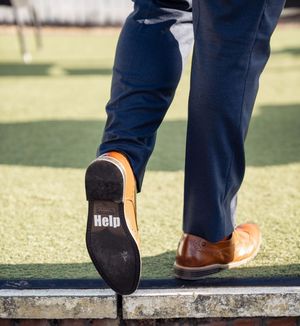 Close-up sequence showing a person's shoes walking on grass in a wedding setting.
