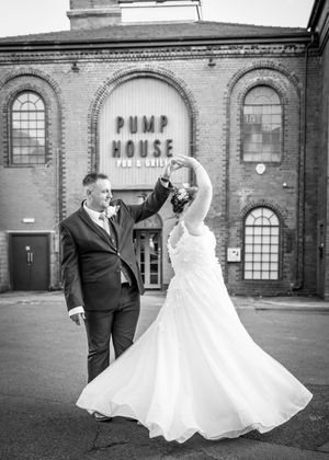 Black and white sequence of a couple dancing in front of a historic brick pump house building.