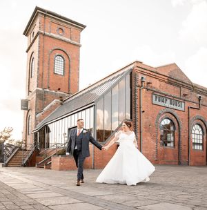 A panoramic view of a red brick industrial building with multiple towers and arches at a wedding venue.