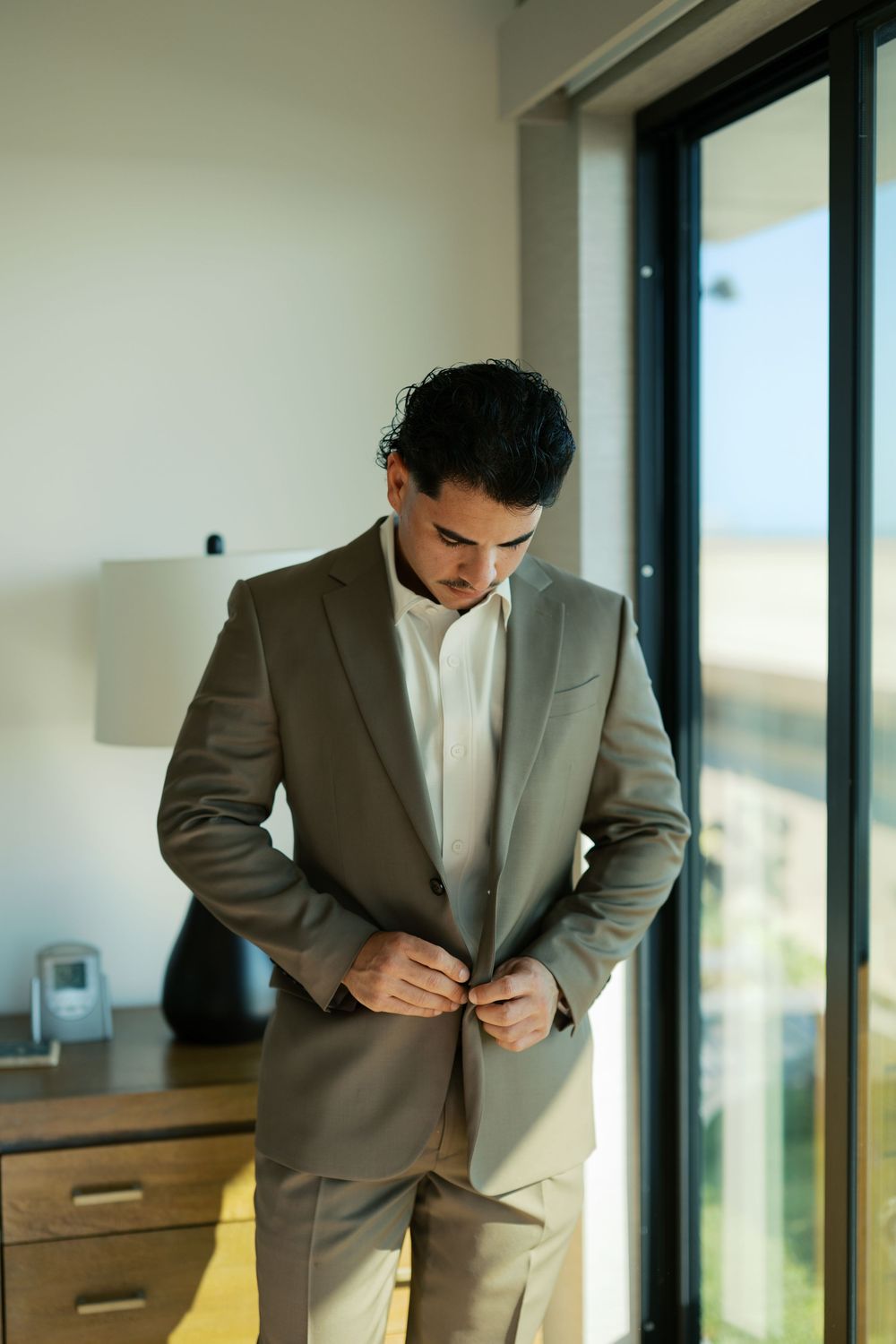 Modern gray suit being adjusted in a sunlit room with contemporary furniture.