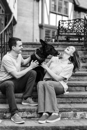 Black and white photo series showing a person sitting on stairs playing with a friendly black dog.