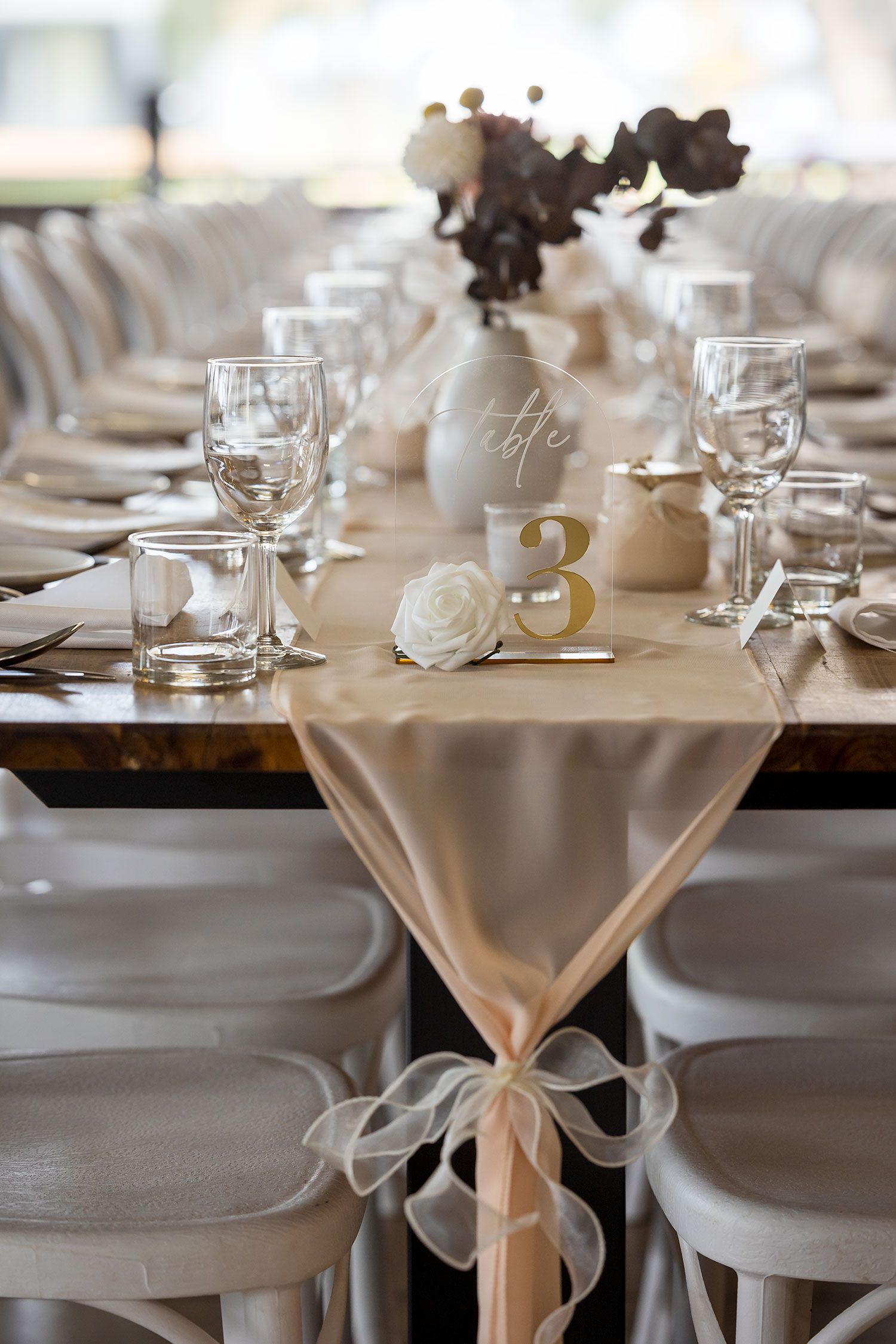 Elegant table setting with white bentwood chairs and floral centrepieces in white vases along a rustic linen tablecloth at Buller Wines.